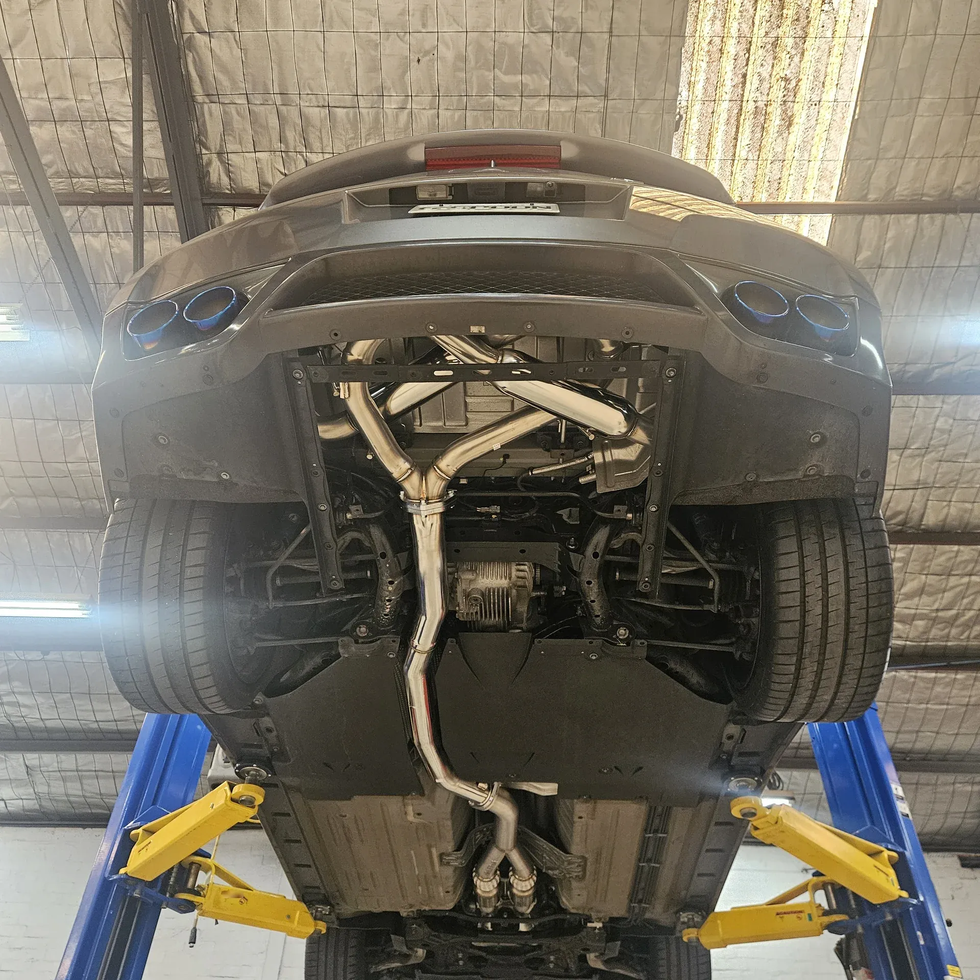 Underside of the R35 GT-R on the hoist with the full stainless exhaust fitted from downpipes to quad titanium tips