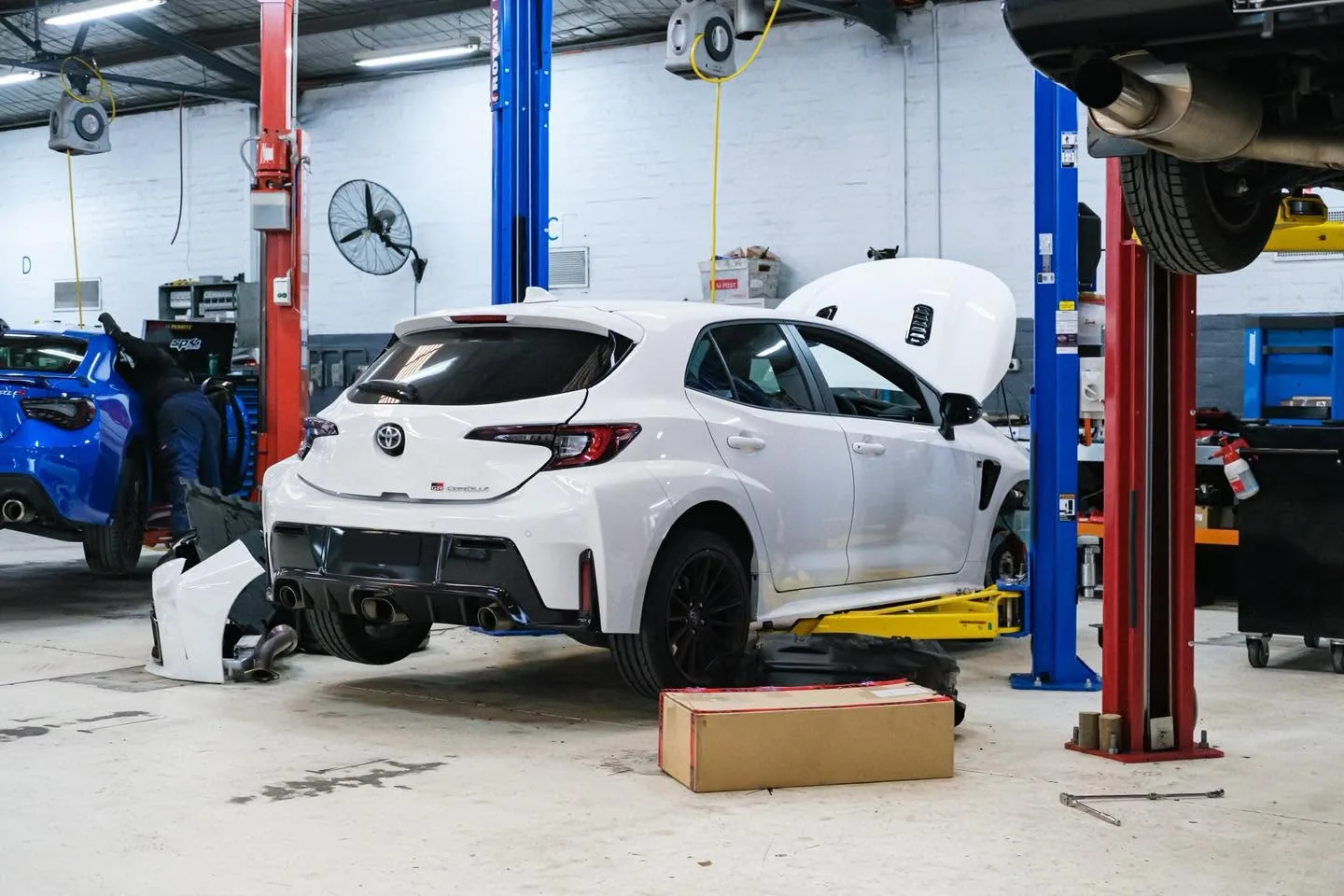 White Toyota GR Corolla in the Revzone workshop with the bonnet up