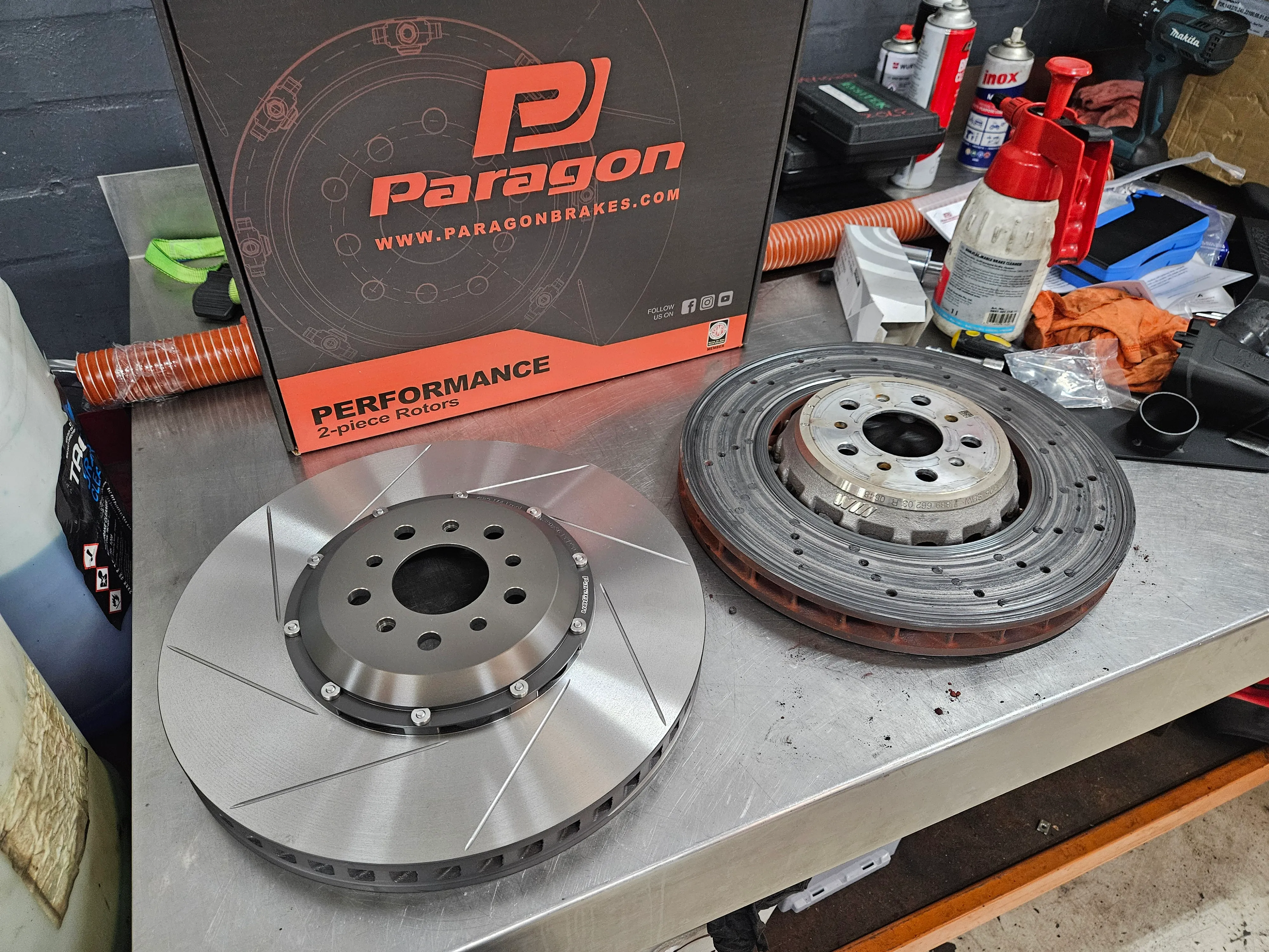 New Paragon 2-piece rotor next to cooked factory rotor on workbench
