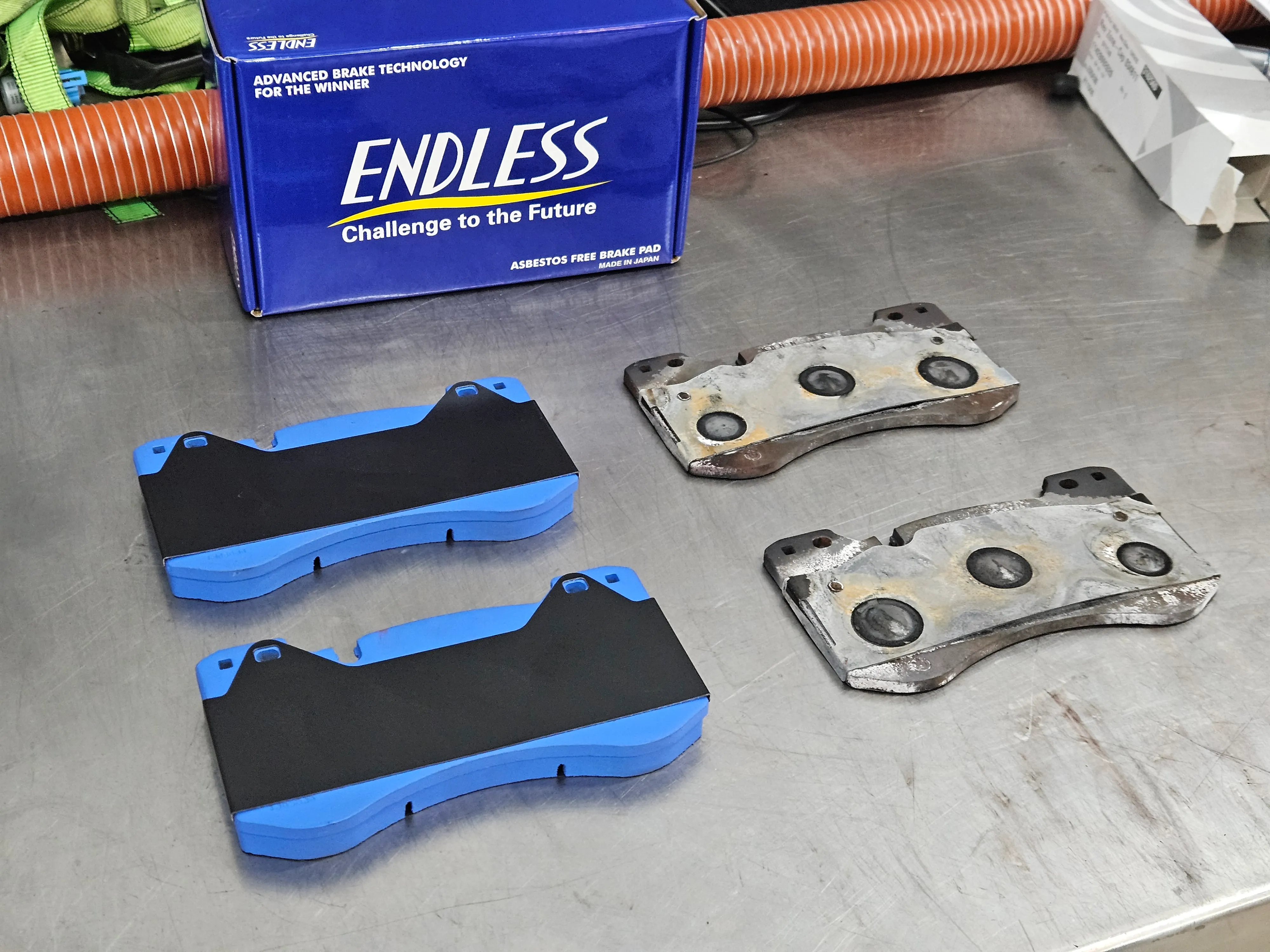 Endless ME20 brake pads next to destroyed factory pads showing pad material loss