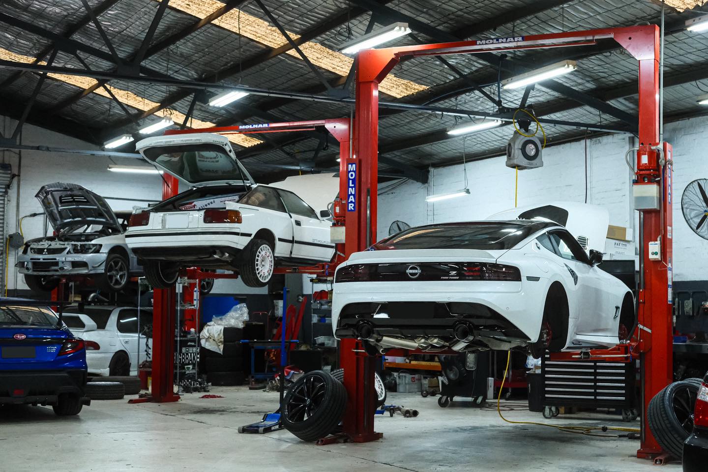 Nissan Z on lift in Revzone Melbourne workshop alongside other builds