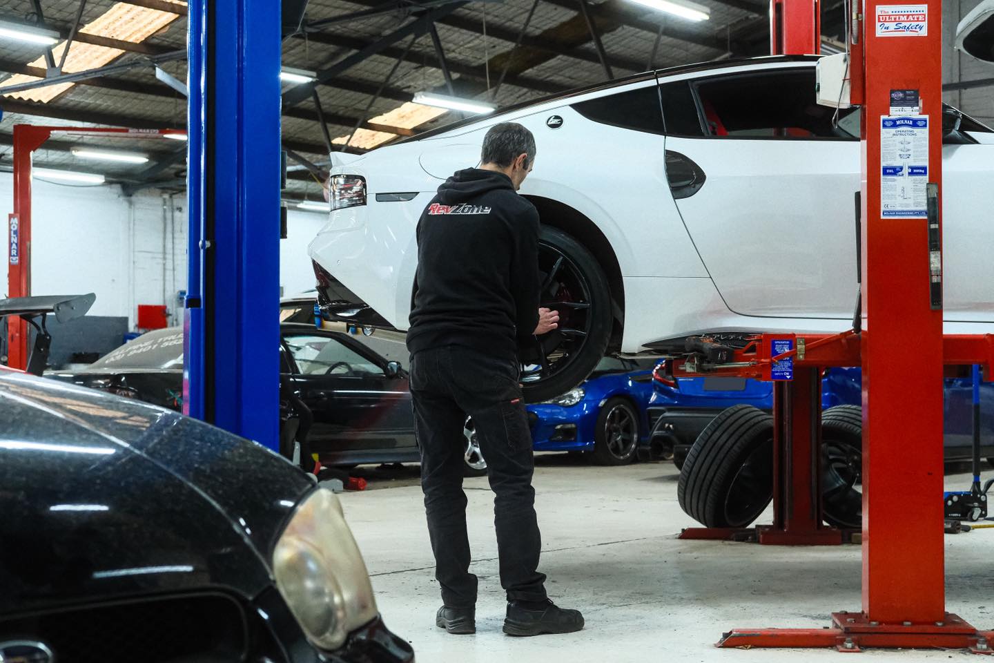Revzone technician refitting wheel on Nissan Z after MCA coilover install