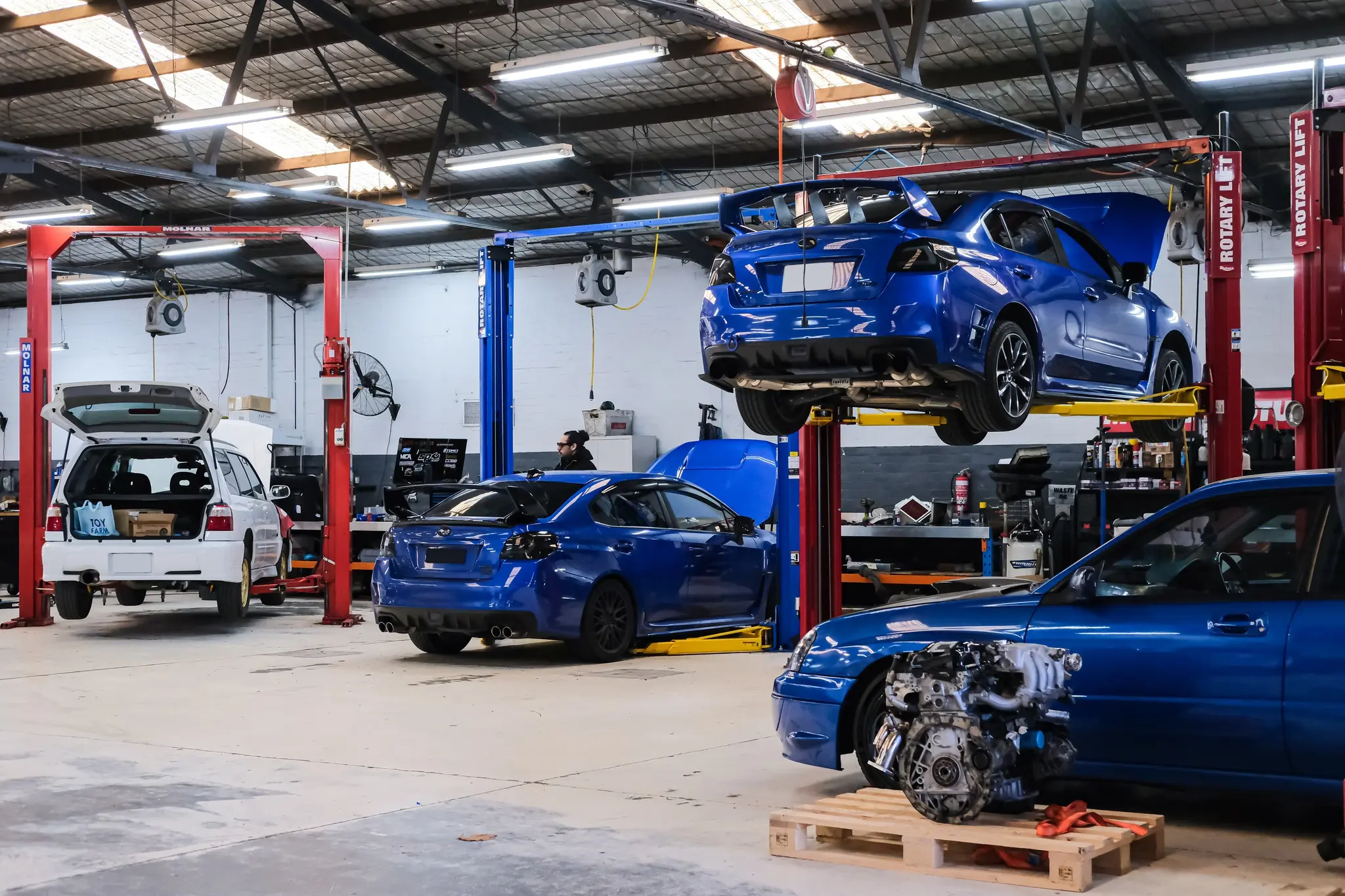 Blue WRX VA on hoist with second WRX on ground level during Stage 2 build